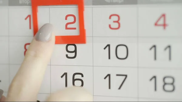 Womans hand in office changes date at wall calendar. 2 Royalty Free Stock Images