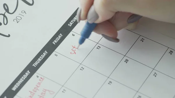 Womans hand writing with red felt pen on calendar word SEX Stock Image