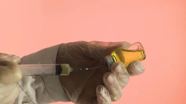 절단 된 부분의 약을 주사기에 넣어 분홍색 배경에 노란 약을 넣는 모습 — 스톡 사진