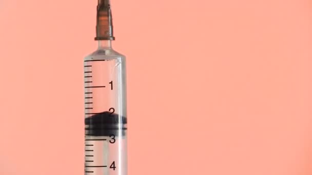Doktor açık iğne ve pembe arka planda serpiştirilmiş ilaçlar — Stok video