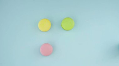 Pastel mavi yüzeyde üç makarna veya badem kurabiyesi