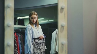 Çekici bayan müşteri soyunma odasında etek seçiyor.