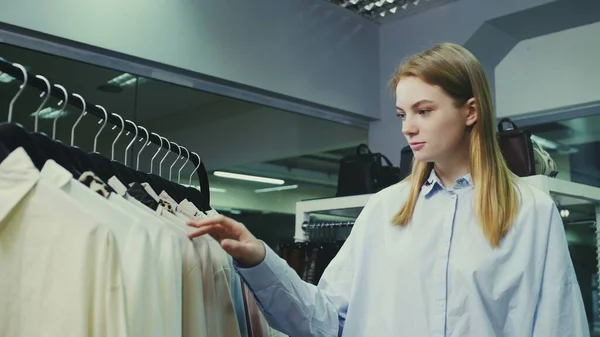 Young pretty girl in boutique selecting clothes to buy. — Stock Photo, Image