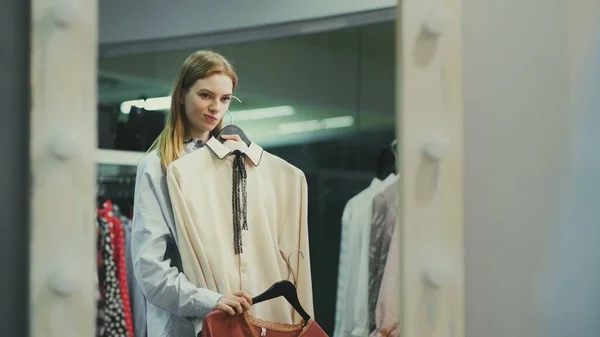 Attractive female customer is trying on blouse in fitting room — Stock Photo, Image