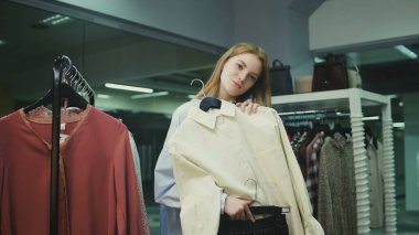 Çekici bayan müşteri aynaya bakıyor ve soyunma odasında bluz deniyor.