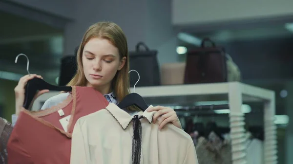 Woman trying on clothes in clothing store. Make choose between red and beige — Stock Photo, Image