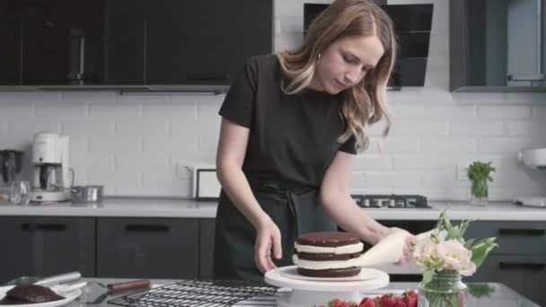 Profi-Koch kocht Kuchen. Junge attraktive Hausfrau legt weiße Sahne auf die Tortenseite — Stockvideo