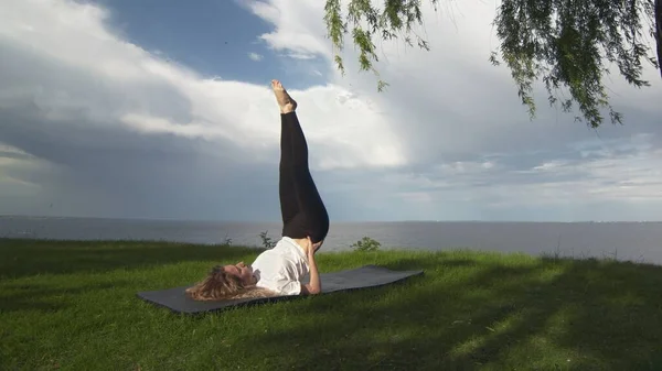 Jovem mulher apto praticar ioga na costa perto do lago ou do mar. Mulher fazendo apoio ombro Stand Pose — Fotografia de Stock