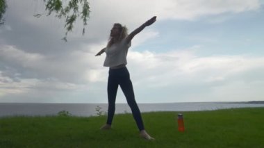 Genç bir kadın deniz kenarındaki yüksek dağ uçurumunda meditasyon ve yoga yapıyor..