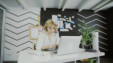 Çekici kadın tasarımcı modern ofiste telefon kullanıyor