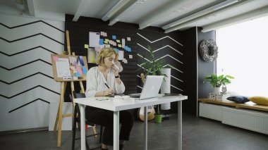 Genç grafik içme suyu ve tablet kullanarak bilgisayar üzerinde çalışma