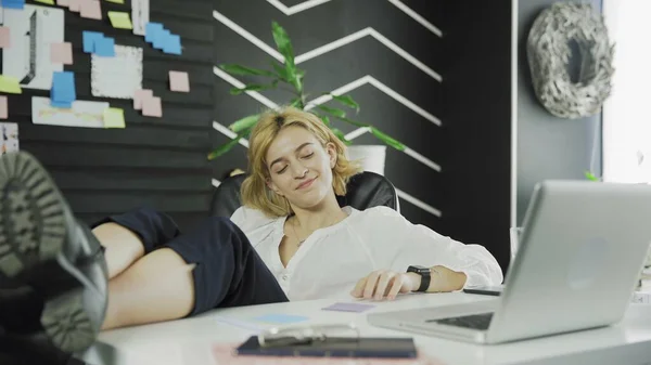 Happy business woman finished her work and puts her legs on the table — Stock Photo, Image