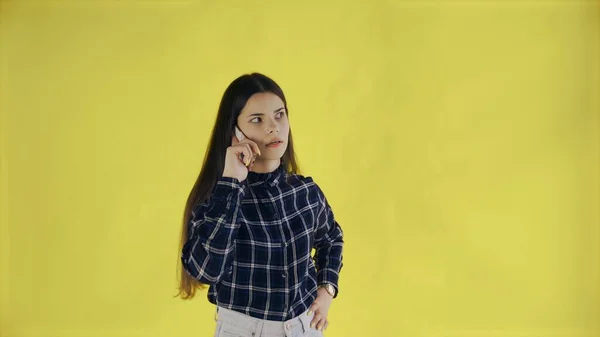 Jonge vrouw staan geïsoleerd over gele achtergrond tijdens het praten per telefoon — Stockfoto