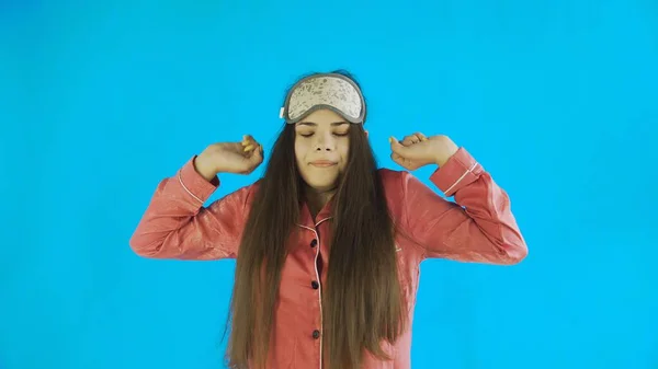 Fiatal gyönyörű lány pizsamában nyújtózkodó kék háttér a stúdióban — Stock Fotó