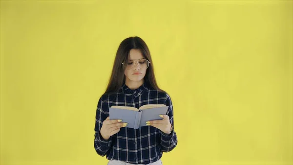 Beautifu вдумлива дівчина читає книгу ізольовано на жовтому тлі — стокове фото