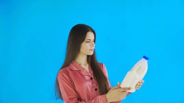 Pijamalı genç kız süt içiyor.