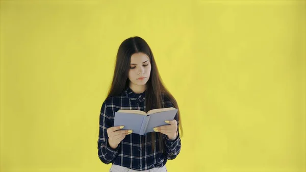 ビューティフー思慮深い女の子は黄色の背景に隔離された本を読んでいます — ストック写真