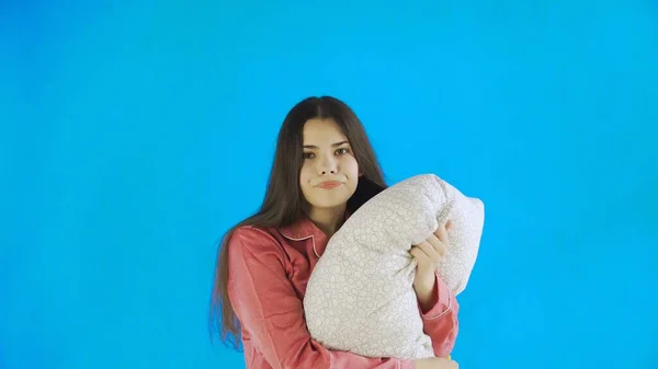 Joven chica bonita con almohada sobre fondo azul en Studio —  Fotos de Stock