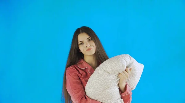 Νεαρό όμορφο κορίτσι με μαξιλάρι σε μπλε φόντο στο στούντιο — Φωτογραφία Αρχείου