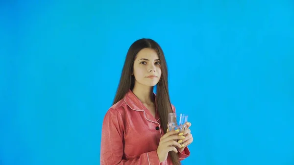 Кавказька дівчина п'є склянку води. Молода жінка п "є воду зі скла на синьому фоні у студії. — стокове фото