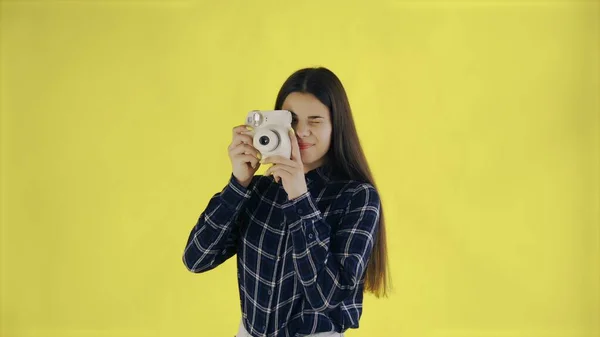 Beautiful Brunette 의 초상화는 스튜디오의 노란 백 그라운드에서 Retro 카메라를 사용하는 것이다. 사진을 찍는 젊은 여자. — 스톡 사진