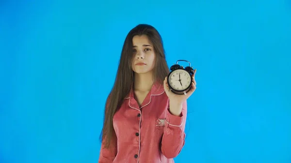 Sleepy woman in pajamas showing alarm clock — Stock Photo, Image