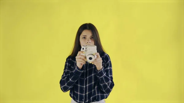 Portrait of Beautiful Brunette is Using Retro Camera on yellow Background in Studio. Young Woman Taking Photo. — Stock Photo, Image