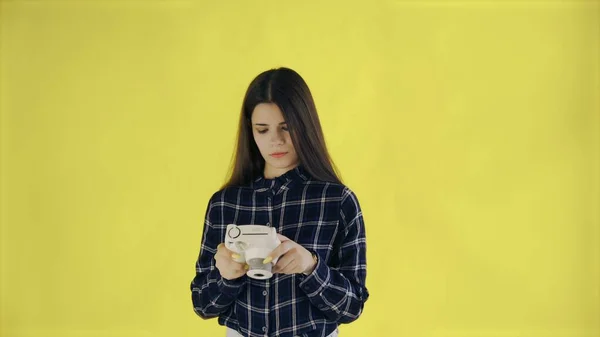 Portretul brunetei frumoase folosește camera retro pe fundal galben în studio. Young Woman Taking Photo . — Fotografie, imagine de stoc