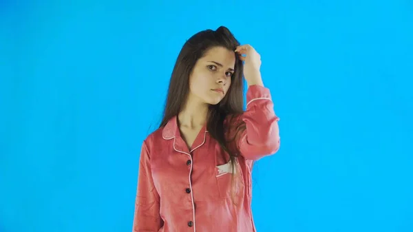 Νεαρή όμορφη γυναίκα αγγίζει τα μαλλιά της σε μπλε φόντο στο στούντιο — Φωτογραφία Αρχείου