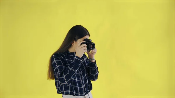Young woman is Taking Photo on yellow Background in Studio