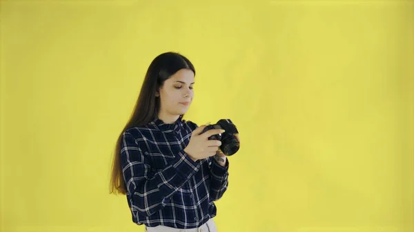 Mujer joven está tomando una foto sobre fondo amarillo en el estudio —  Fotos de Stock