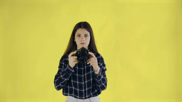 Jeune femme regardant la caméra et prenant des photos sur fond jaune dans Studio — Photo