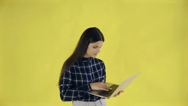 Young girl working on laptop checking social media in casual clothing on yellow Background in Studio — Stock Photo, Image