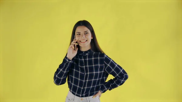 Mujer feliz de pie aislada sobre fondo amarillo mientras habla por teléfono —  Fotos de Stock