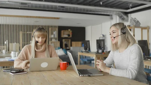 Two female office workers are talking with customer with headphones — Stock Photo, Image