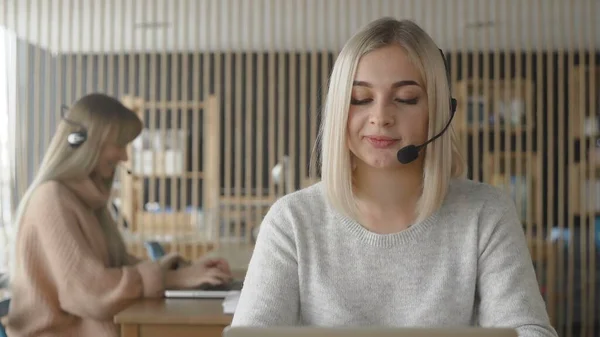 Two technical support specialist talking with customers by headsets. — Stock Photo, Image