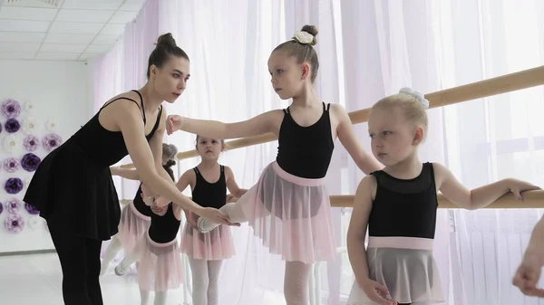 Teachers show how to dance to little ballerinas. Girl dancer in ballet school learns to dance. Young ballerinas jumping in training. School of ballet.