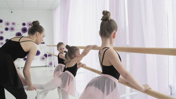 Jovens dançarinas de balé estão fazendo plie e tendão battement enquanto sua professora está corrigindo posições erradas e dando instruções . — Fotografia de Stock