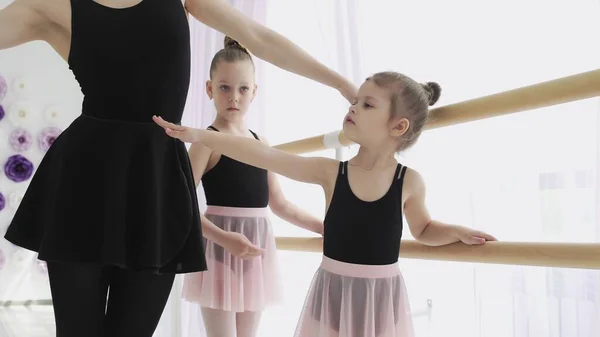 Женщина и девочки в балетной школе. Взрослая балерина, практикующая с маленькими девочками и обучающая русский классический балет — стоковое фото