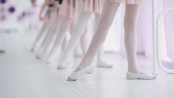 Close up feet of unrecognizable little girls in white socks and ballet shoes, their ballet teacher correcting them — Stock Photo, Image