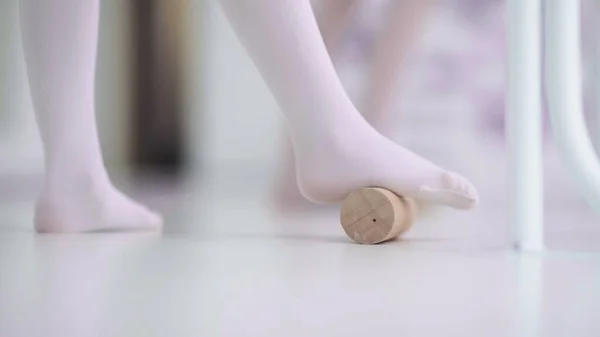 Girl is using wooden roller to massage her feet — Stock Photo, Image