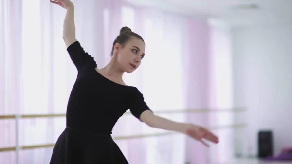 Uma bailarina profissional em um pacote preto dança em um grande salão de treinamento — Fotografia de Stock