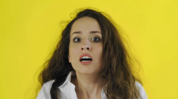 Portret van een jonge geschokte, bange en bange vrouw op gele achtergrond in de studio. — Stockfoto