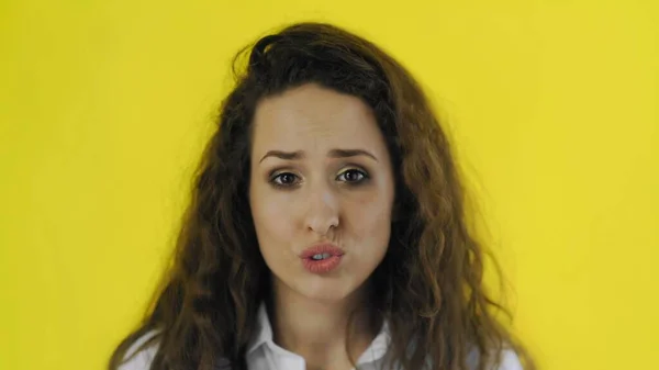 Young beautiful disappointed woman posing on camera on yellow background. — Stock Photo, Image