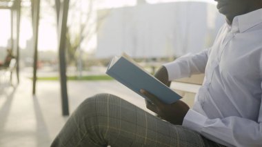 Genç Afrikalı işadamı park yerinde kitap okuyor.