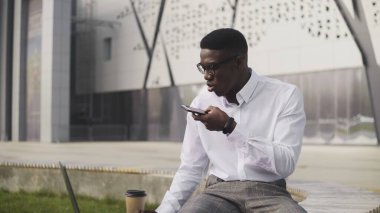 Parkta sesli mesaj kaydeden akıllı Afrikalı iş adamı