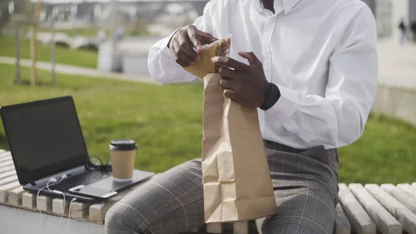 Empresário Africano Usando Laptop ao ar livre enquanto almoça — Fotografia de Stock
