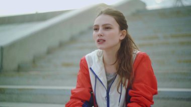 Çekici kadın koşucu merdivenlerde oturuyor ve yoğun antrenman sonrası yorgun dinleniyor.