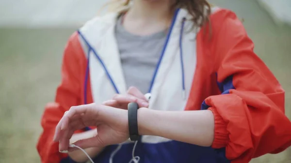 Woman is changing music on her smartwatch and wearing headphones — Stock Photo, Image