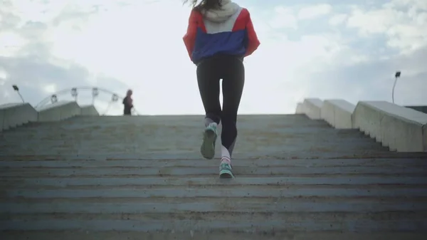 Baksidan av kvinnan i sportkläder springer trappor. Elegant kvinna springa trappor i sity park. — Stockfoto